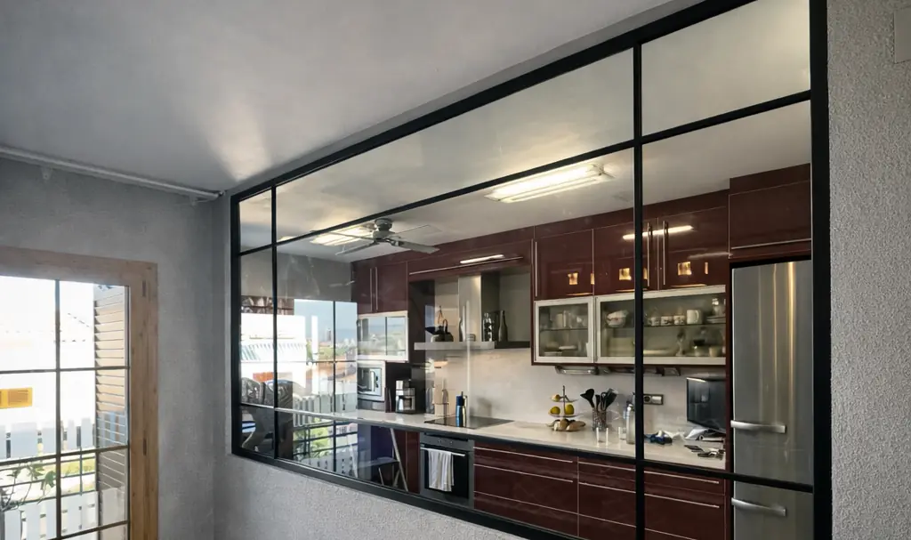 Cristalera de estilo industrial con perfil negro entre la cocina y el salón