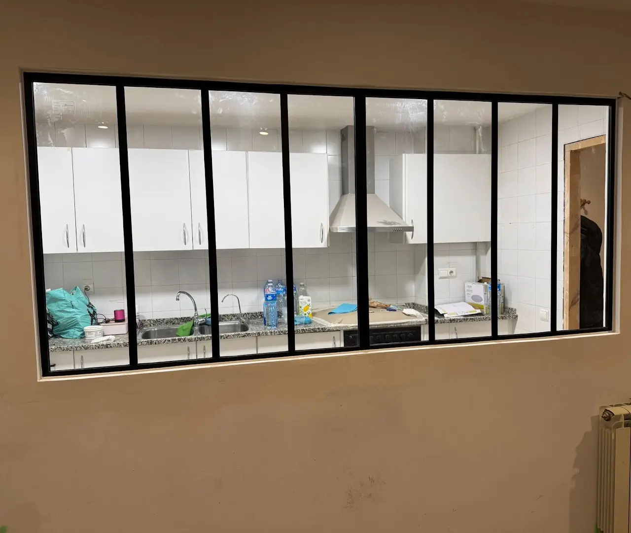 Ventana interior de vidrio con perfil negro abierta a la cocina